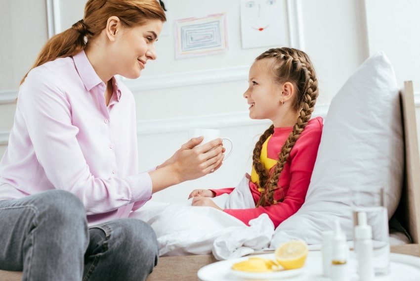 mother giving drink to sick daughter