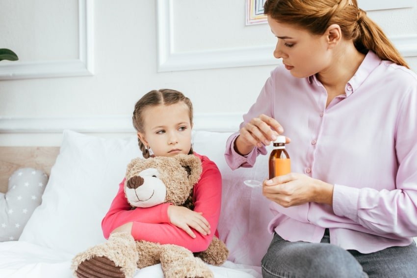 mother giving medicine to daughter